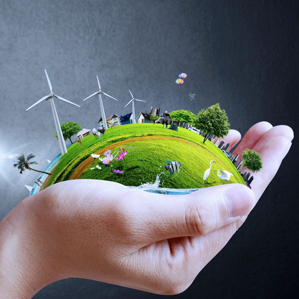 Hand holding miniature green world with wind turbines